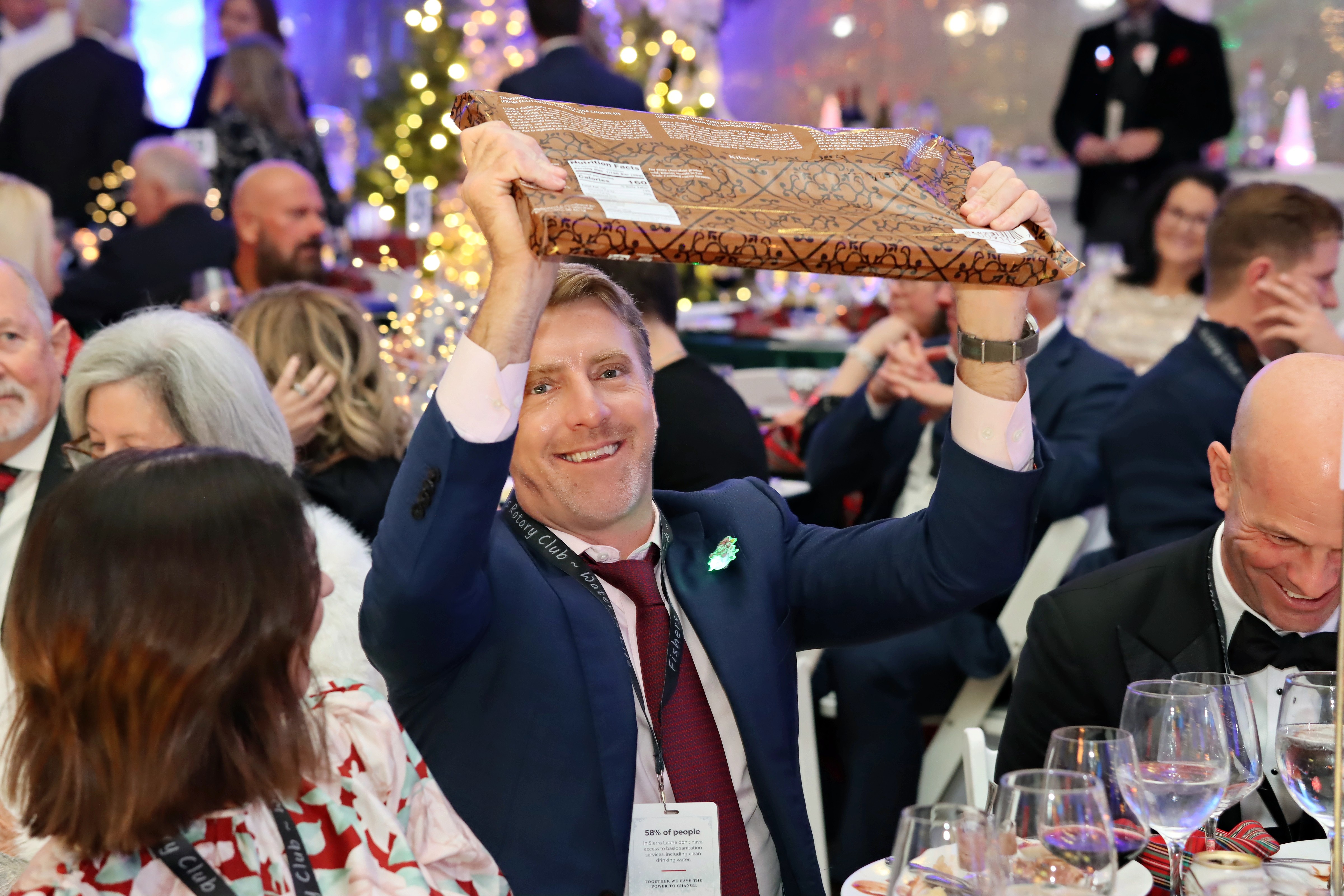 A Charity Ball guest celebrates while holding an auction package above his head